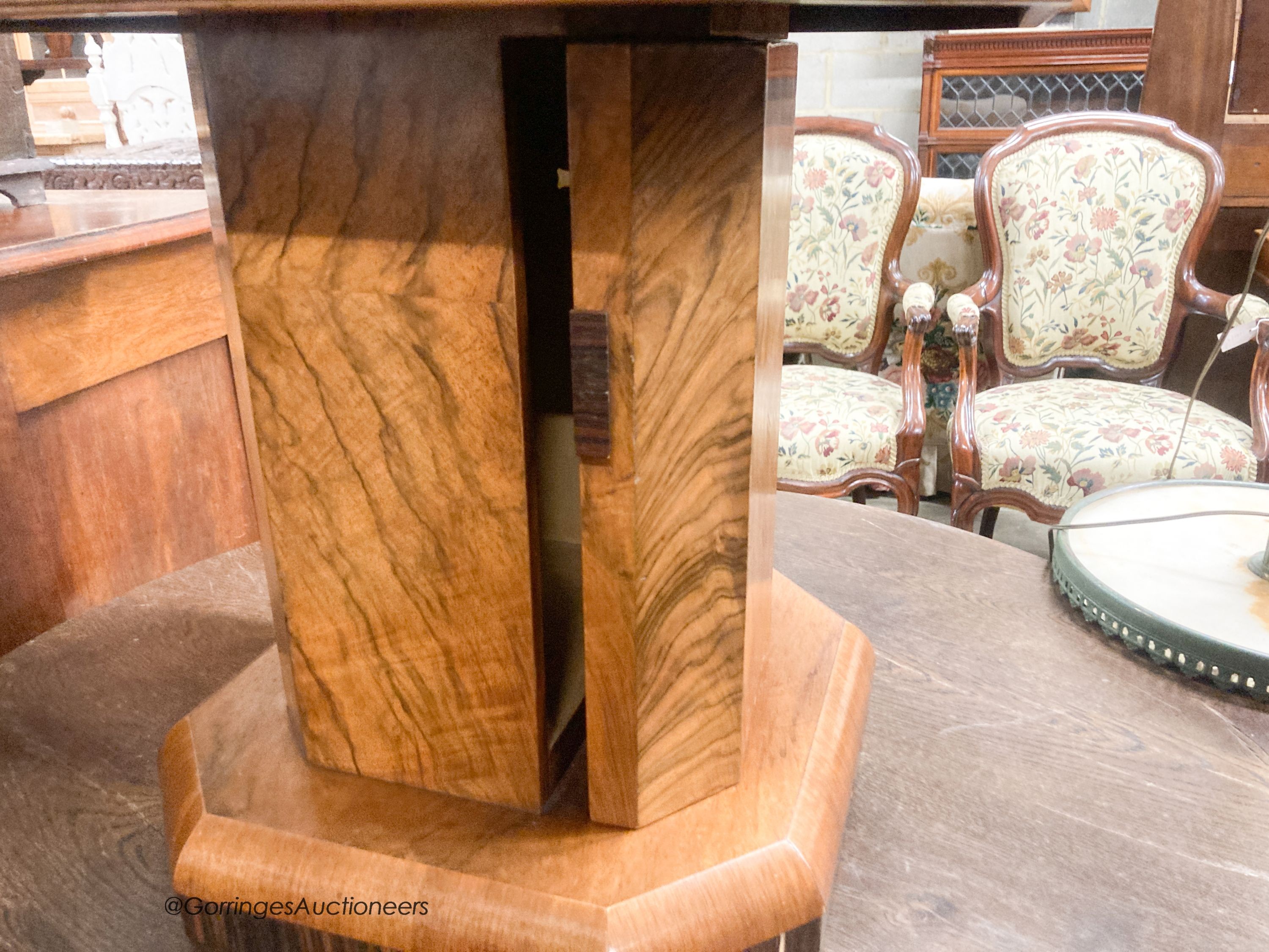 An Art Deco style octagonal figured walnut coffee table, with cupboard column, width 57cm, height 51cm